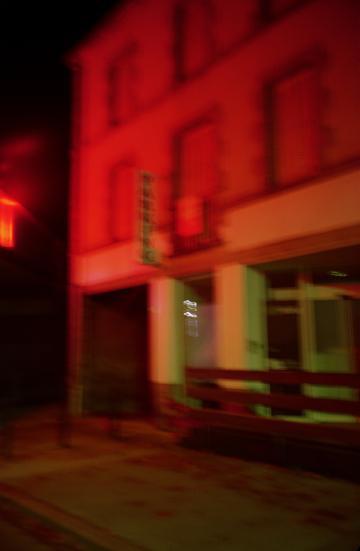 immeuble de nuit eclaire en rouge dans une ambiance de polar